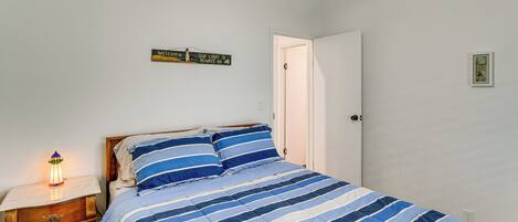 Un dormitorio con cama, mesita de noche y un cartel en la pared.