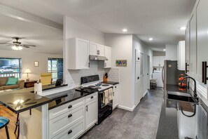 A modern kitchen with white cabinets, a black countertop, and a stainless steel range hood.