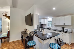 A modern kitchen with white cabinets, a black countertop, and a dining area with two chairs. - Near Boat Ramp, Kingfisher Park/pier, Dog Friendly (Port O Connor)