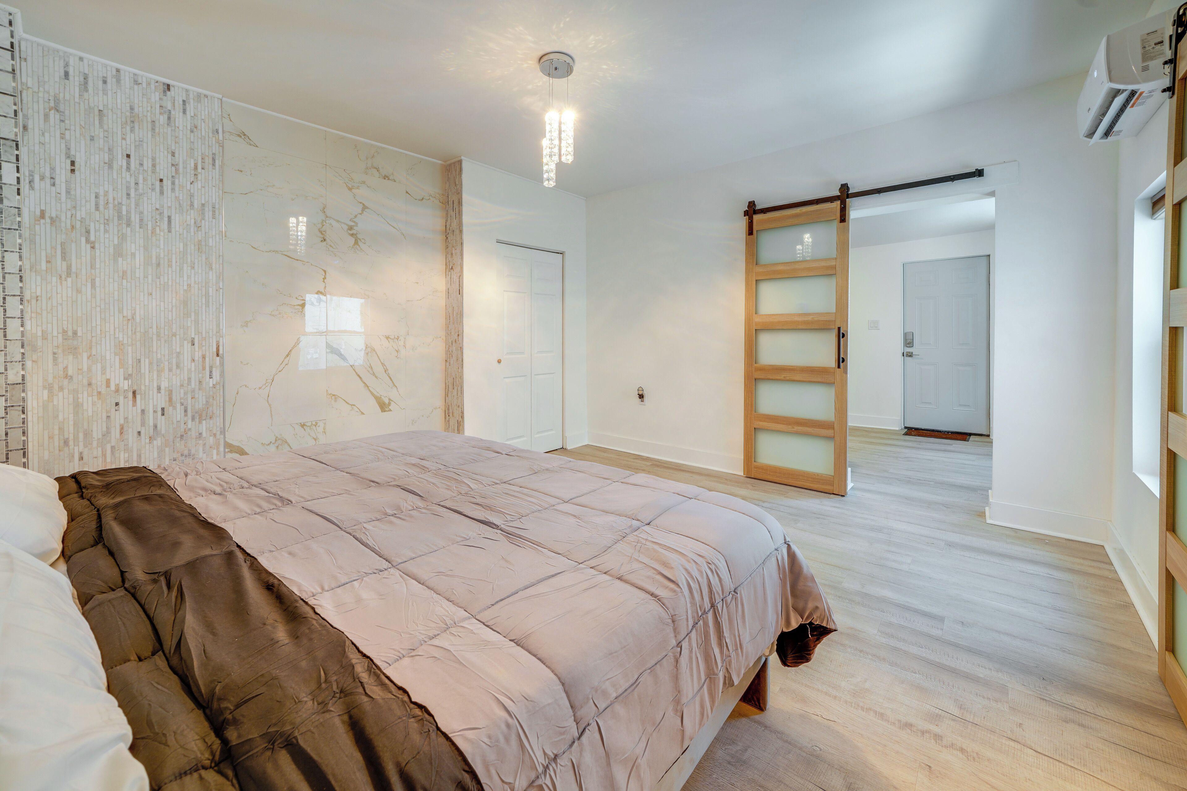 A bedroom with a large bed, a sliding door, and a wooden floor.