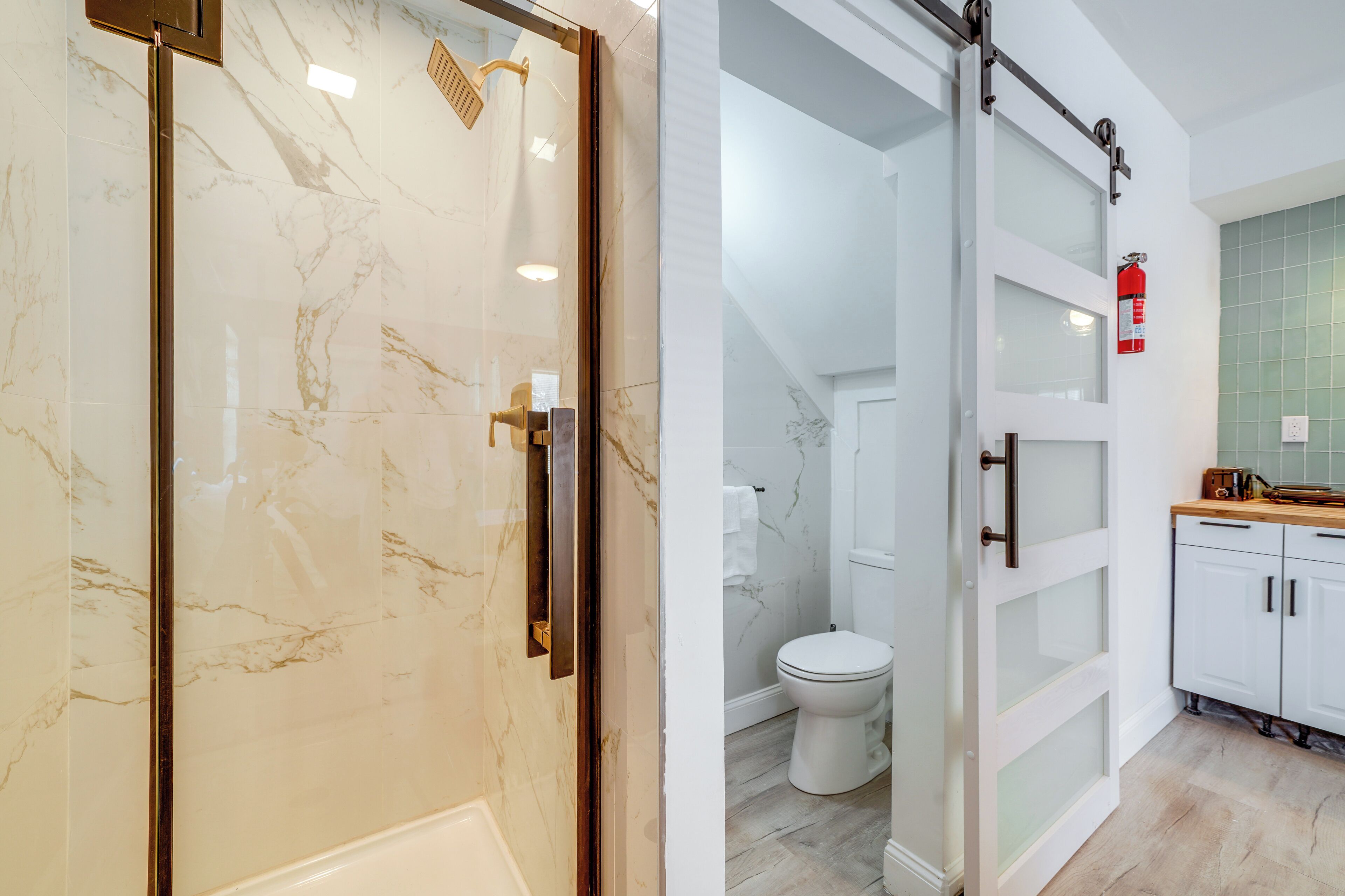 A modern bathroom with a glass shower enclosure, a toilet, and a sink area with cabinets.