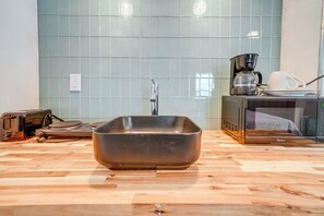 A modern kitchen with a large rectangular sink, a coffee maker, and a microwave on the counter. - Walkable Location! High-end 4-unit Hinton Getaway (Hinton)