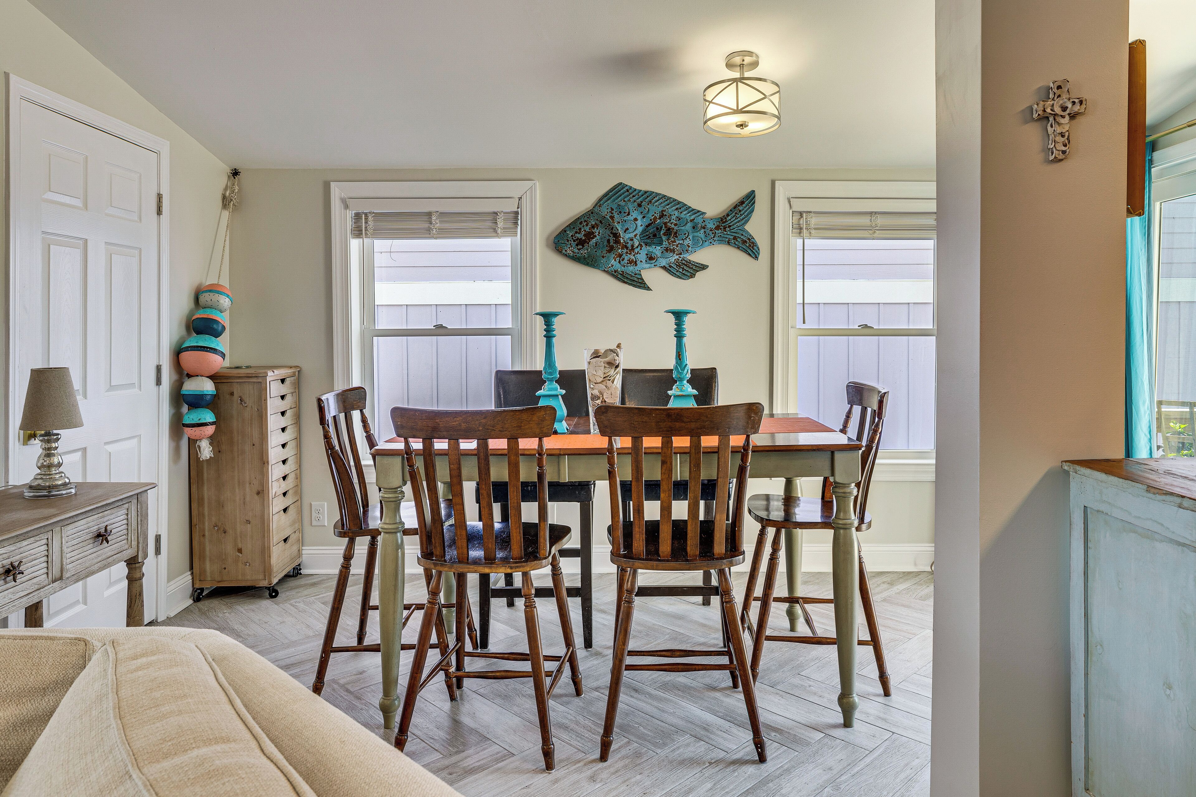 Un coin repas avec une table et des chaises en bois, une décoration murale représentant des poissons et un meuble en bois.