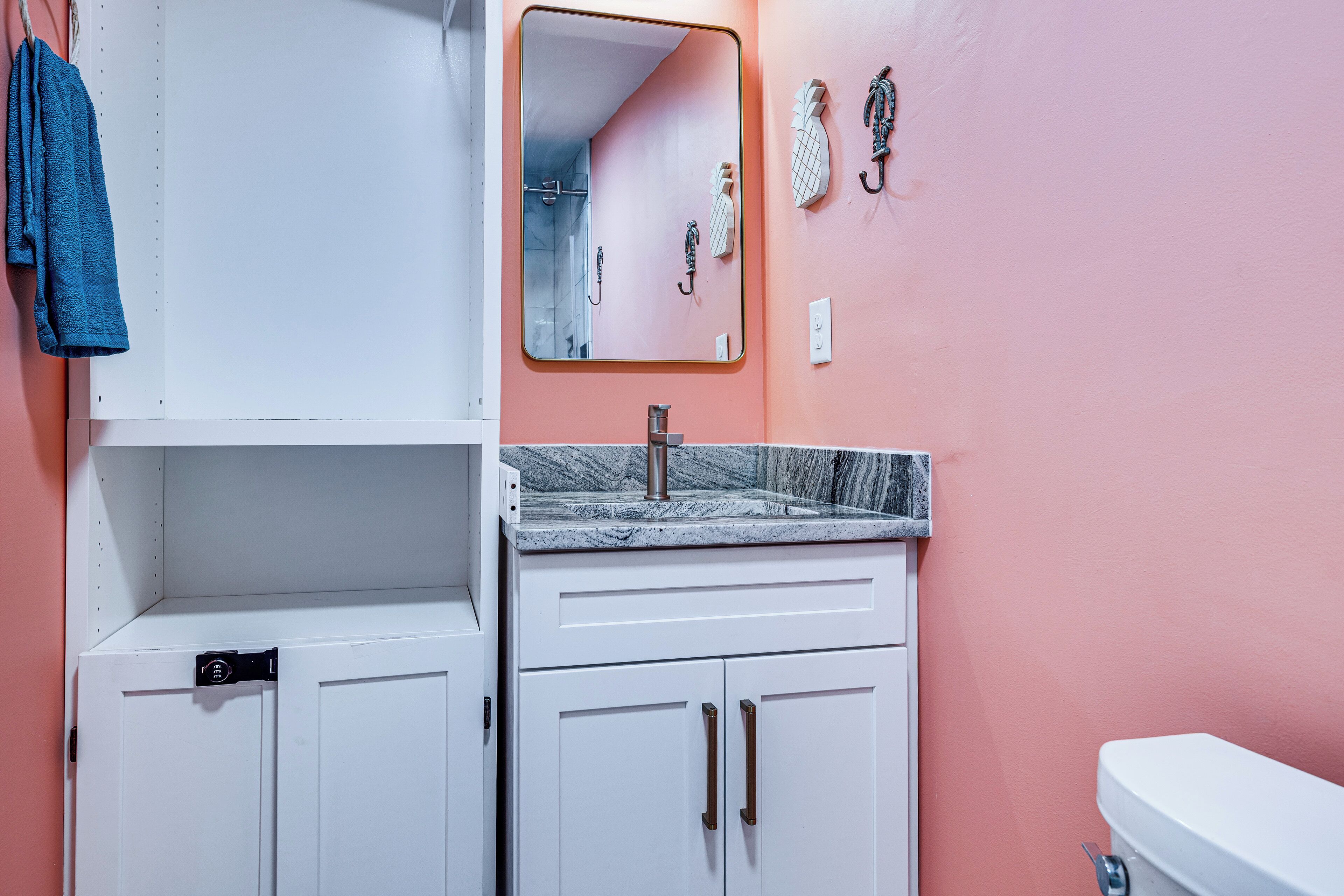 Ein Badezimmer mit einem weißen Waschbecken, einem Spiegel und einer Toilette.