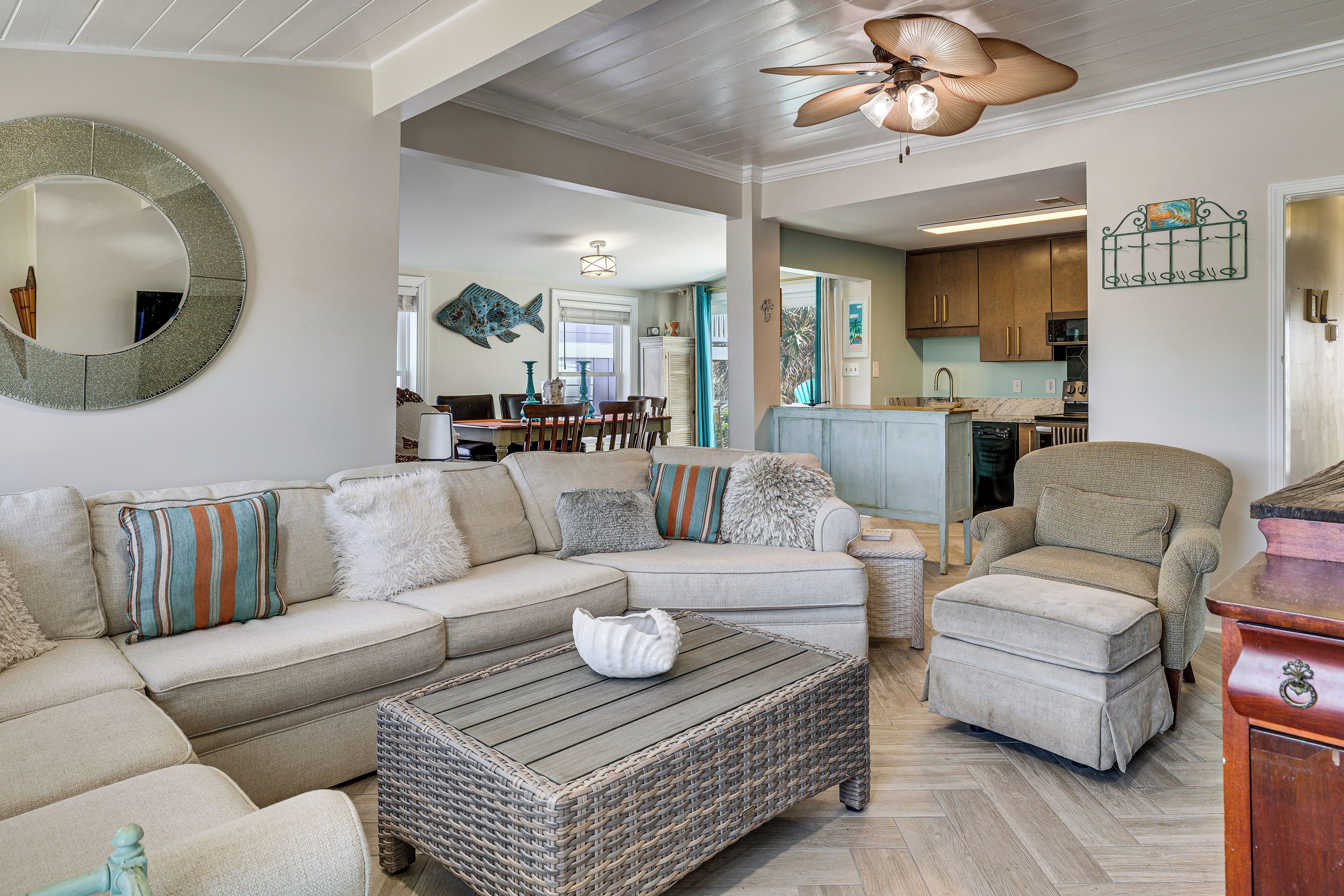 A living room with a sectional sofa, a chaise lounge, a coffee table, and a wicker ottoman.