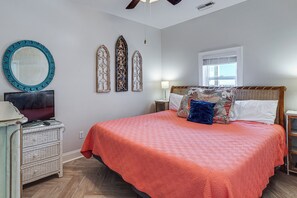 Un dormitorio con cama, televisor, cómoda y decoración en la pared.