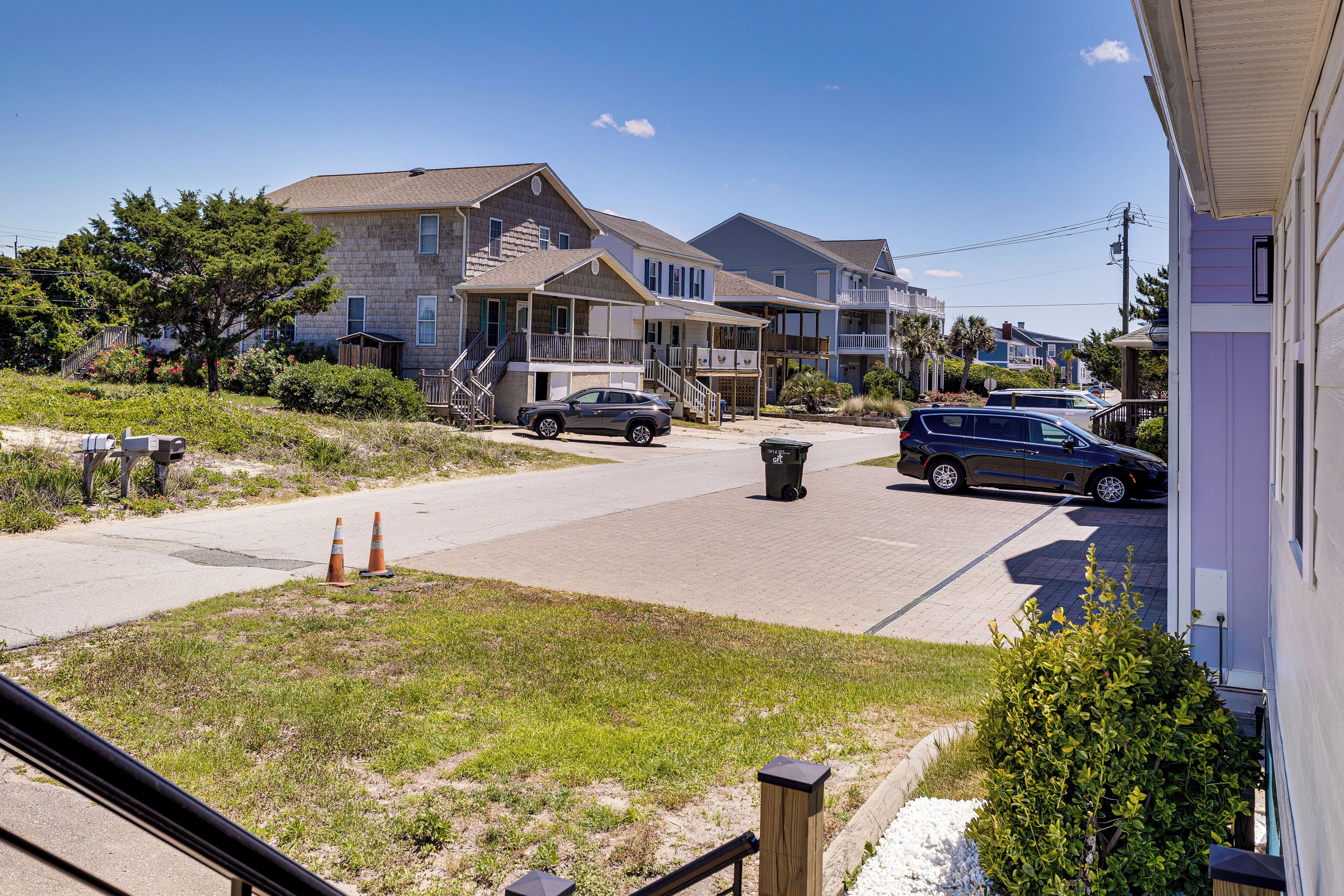 A residential street with houses, a clear sky, and a parked car.