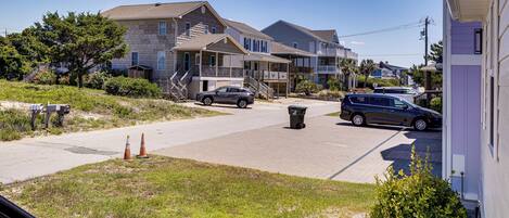 A residential street with houses, a clear sky, and a parked car.