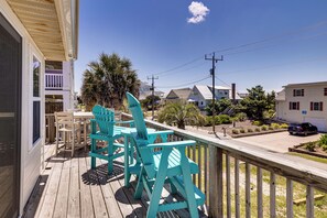 A wooden deck with turquoise chairs, a table, and a view of houses and a car in the background. - Red, White & Beach! 5BR Atlantic Beach Cottage (Atlantic Beach)