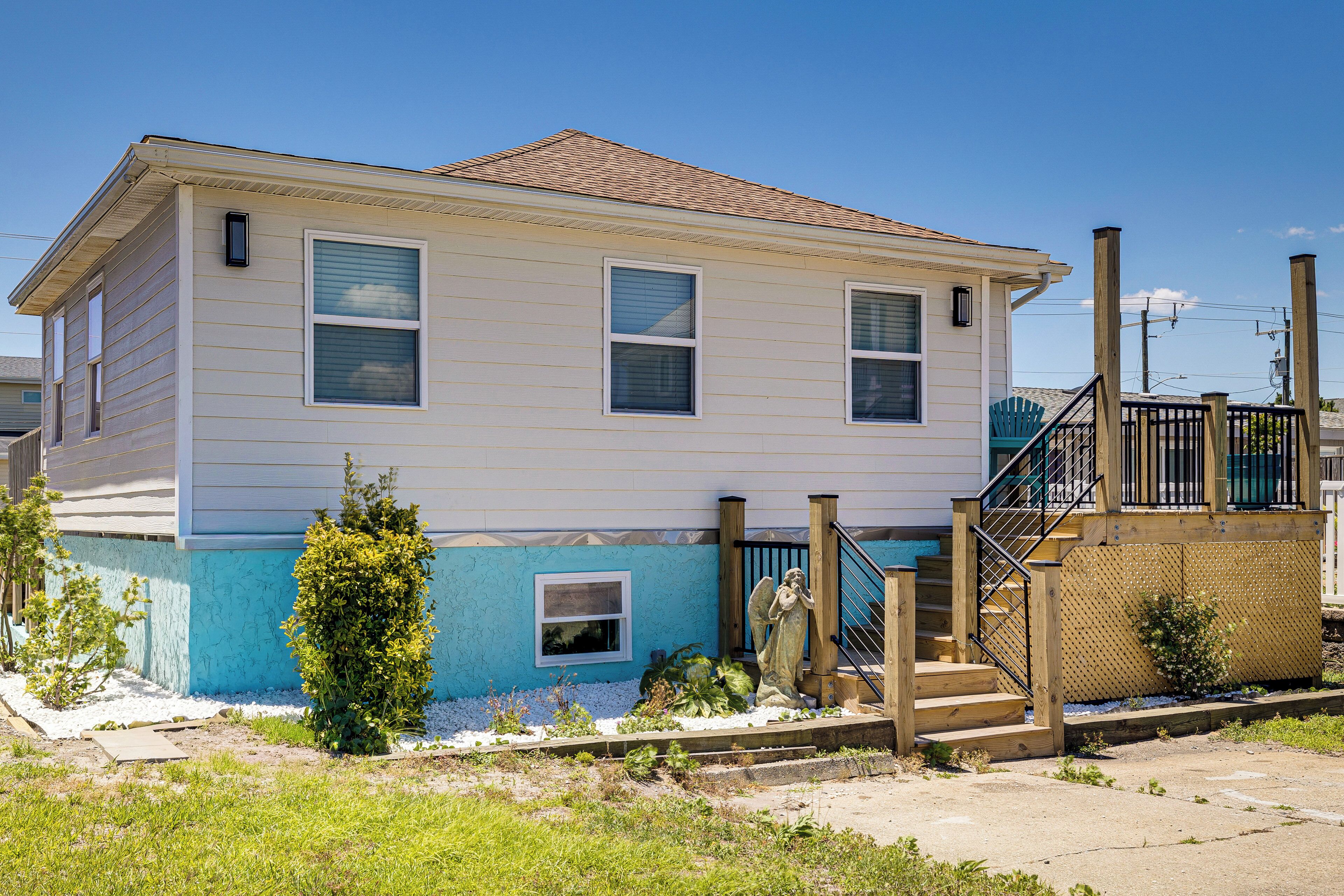 A two-story house with a blue and white exterior, a small front yard, and a wooden staircase leading to the front door.