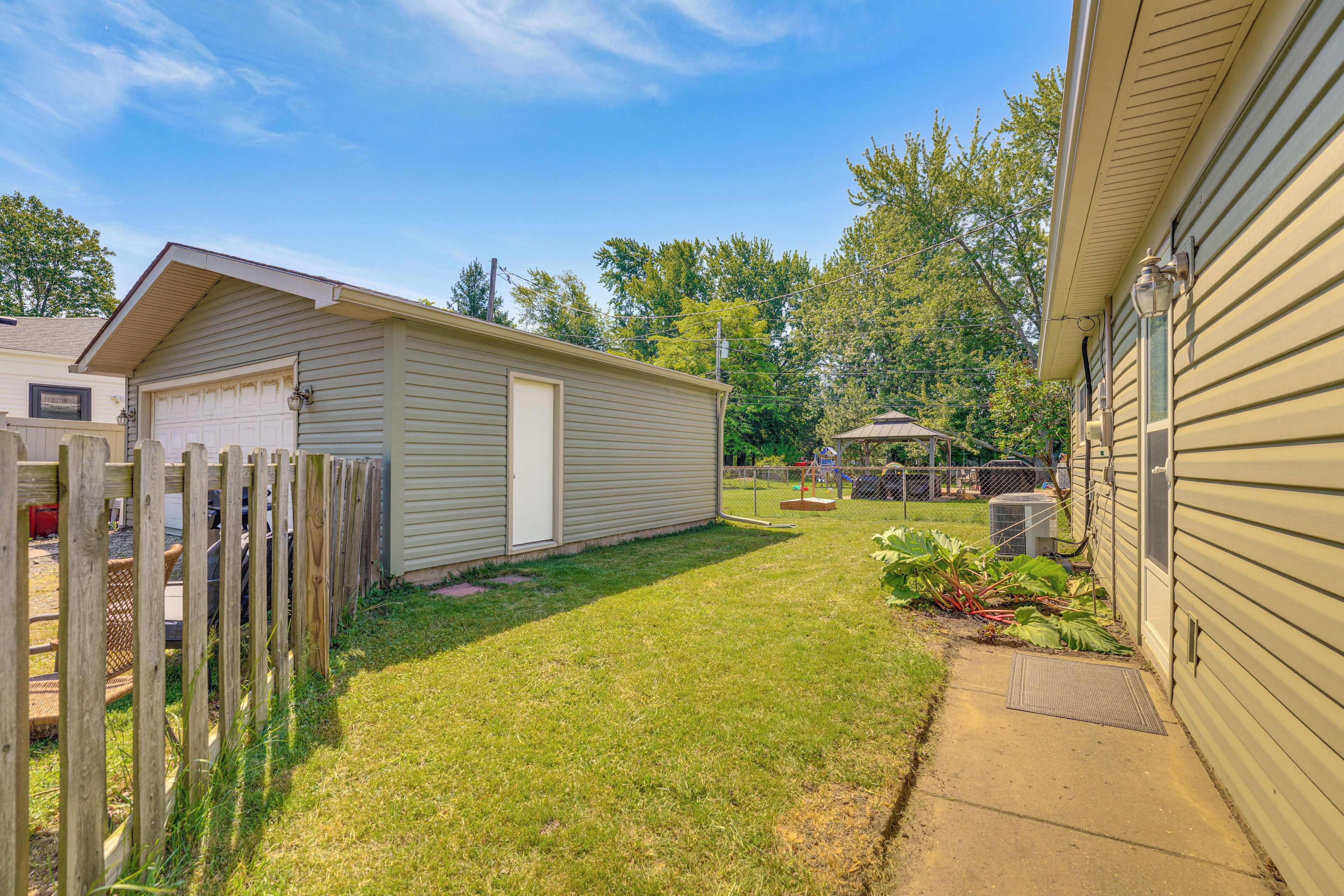 A residential backyard with a fenced area, a shed, and a pathway leading to a house.