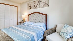 A bedroom with a bed, a nightstand, a lamp, a chair, and a closet.