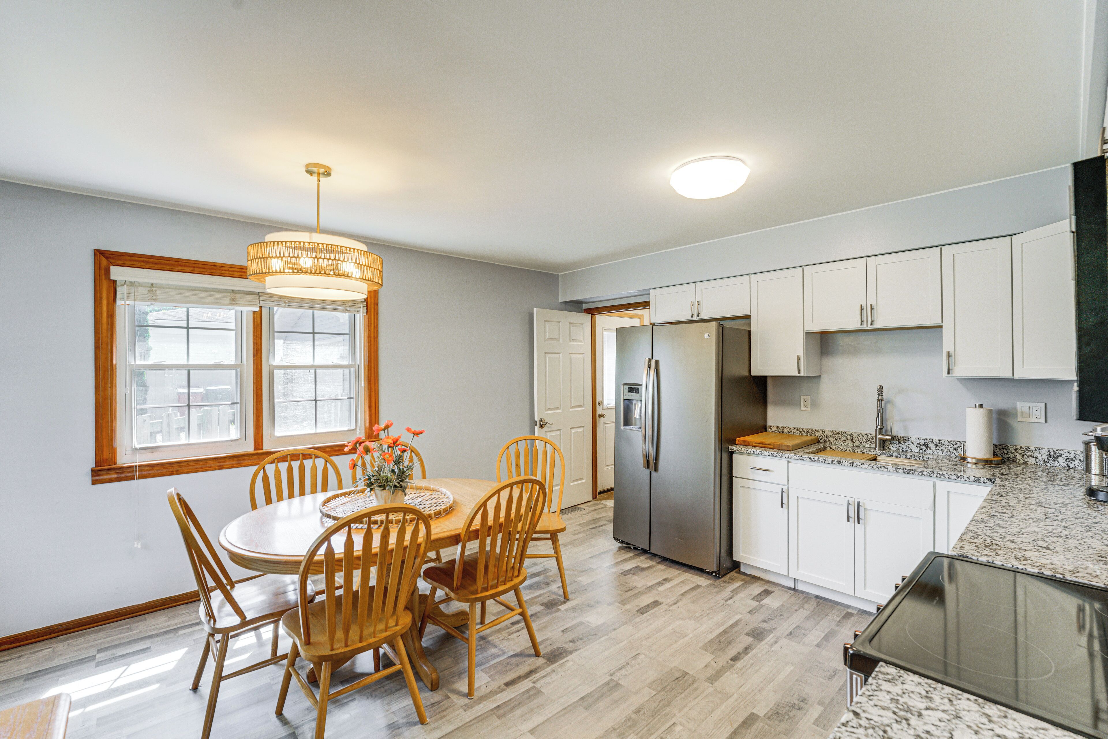 A kitchen with a dining table, chairs, a refrigerator, and a granite countertop.