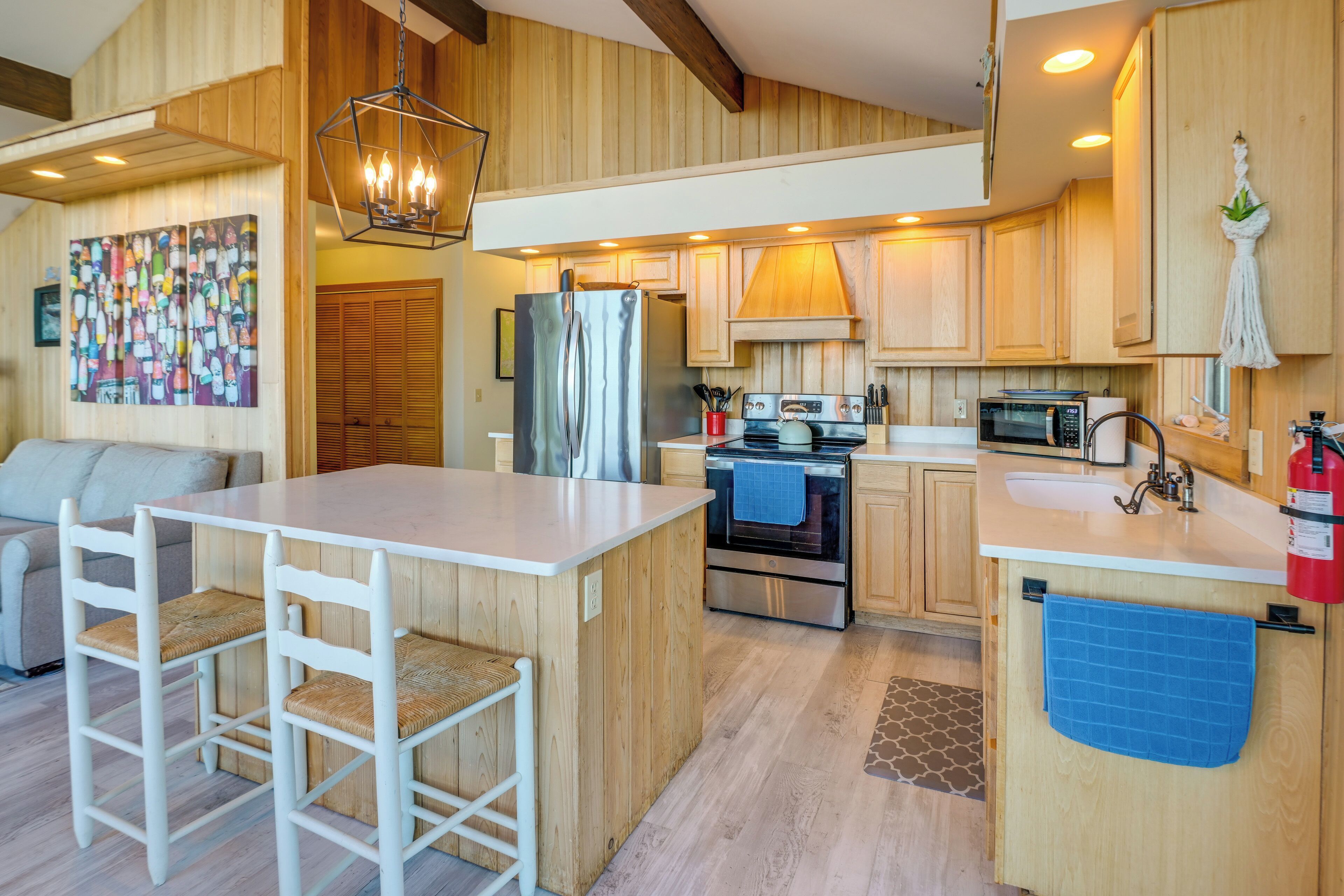 A compact kitchen with a central island, wooden cabinetry, a refrigerator, stove, and a microwave.