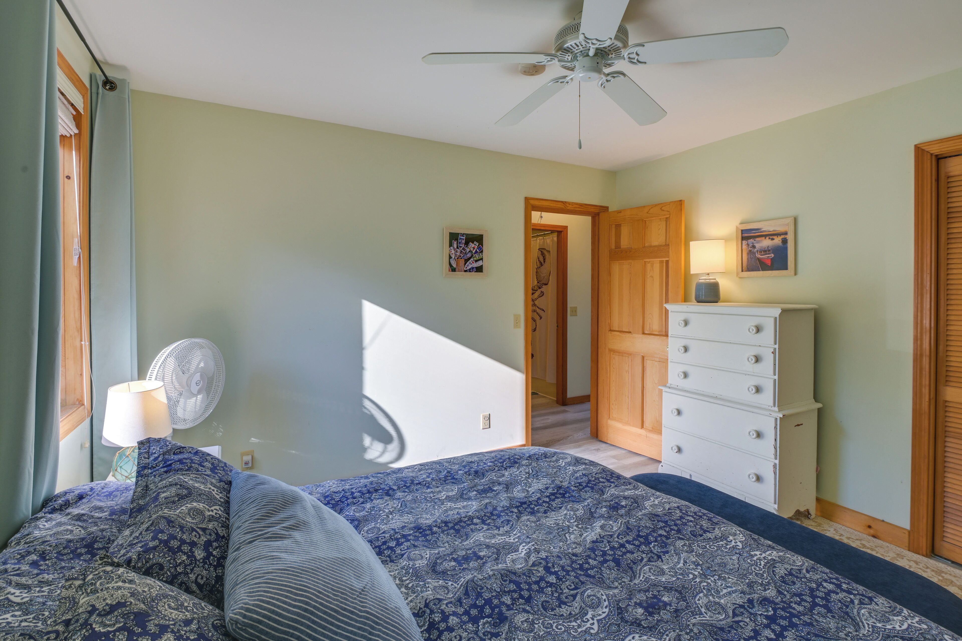 Un dormitorio con cama, cómoda, ventilador y escalera.