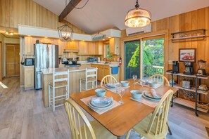 Eine geräumige Küche mit Holzausstattung, einer zentralen Kochinsel und einem Essbereich mit Holztisch und Stühlen.
