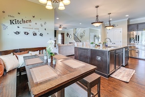A modern kitchen with a dining area, wooden furniture, and decorative wall art.