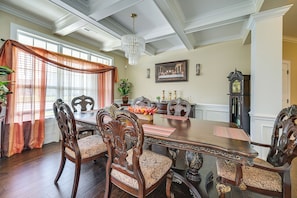 A dining room with a wooden table, ornate chairs, a chandelier, and a large framed picture on the wall.