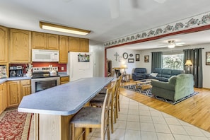 A kitchen with wooden cabinets, a microwave, and a dining area with a table and chairs.
