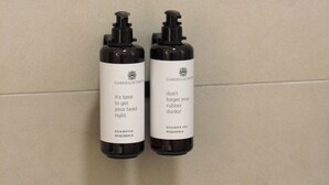 Dos botellas negras con etiquetas blancas sobre un muro de azulejos.