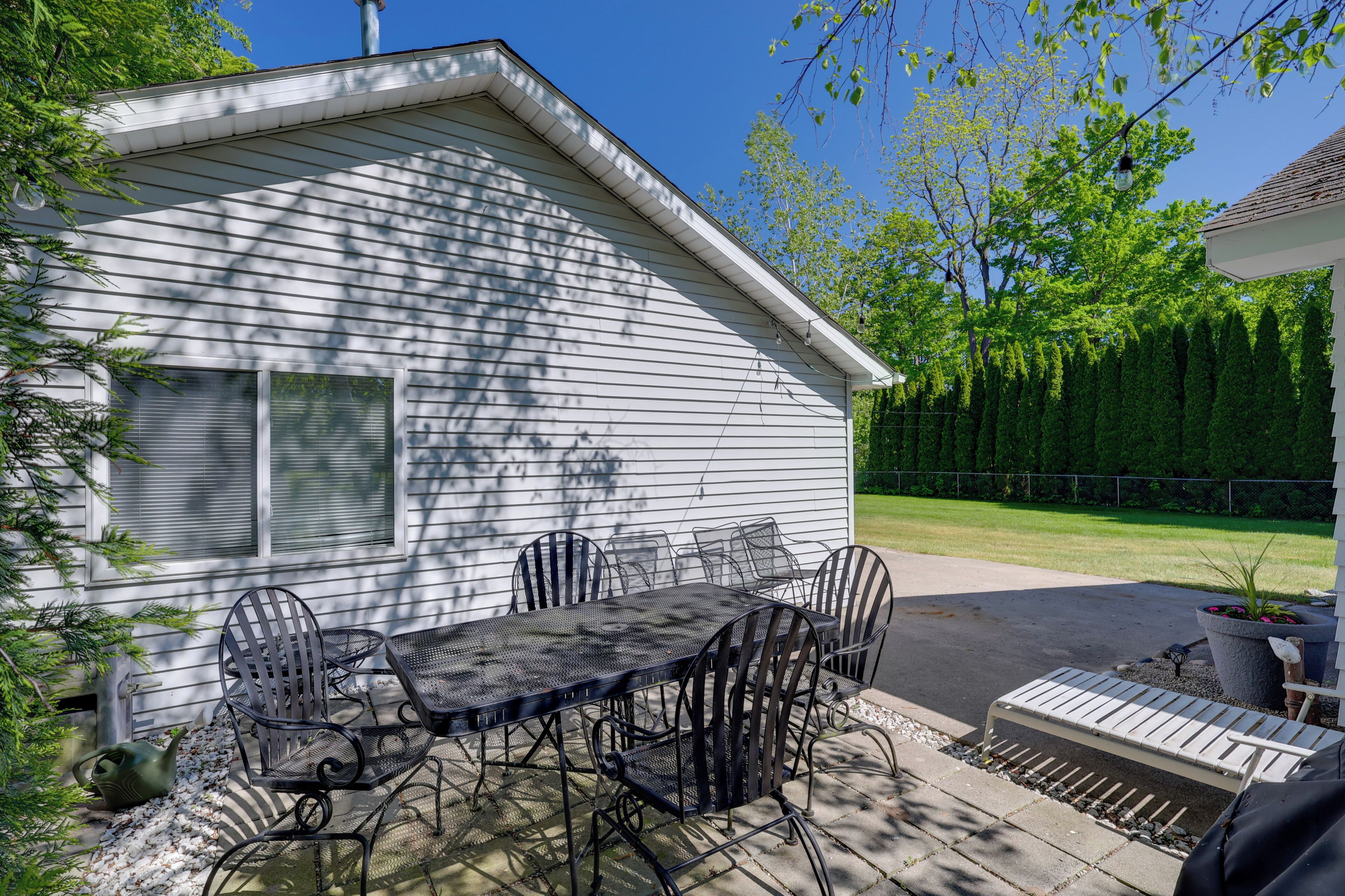 Une terrasse avec une table et des chaises, un pot de fleurs et un petit espace aménagé en jardin.