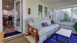 A cozy room with a bed, a small table, and a view of the outdoors. - Cute Cottage Getaway; Walk to Lake and Town (Port Sanilac)