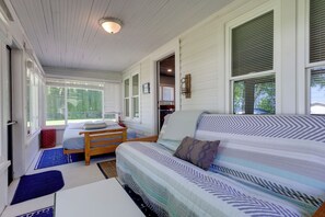 A bedroom with a bed, a wooden bench, a small table, and a window with blinds.