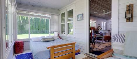 A bedroom with a wooden bed, a blue patterned rug, and a view of the outdoors.