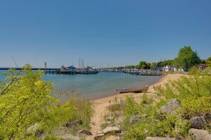 Un port de plaisance avec des bateaux amarrés, une plage de sable et de la verdure.