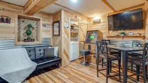 Interior acogedor de una cabaña con sofá, mesa de comedor y lavadora.