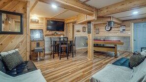 Un interior de madera con mesa de billar, zona de estar y televisor.