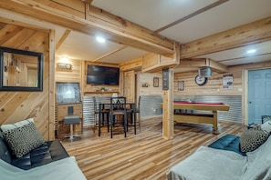 A wooden interior with a pool table, seating area, and a television.