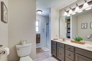 A bathroom with a toilet, sink, mirror, and shower.