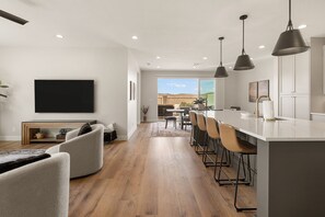 Eine moderne Küche mit Bar, Essbereich und Wohnzimmer mit Flachbildfernseher.