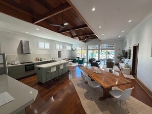 Une cuisine moderne dotée d’un îlot central, d’un coin repas avec une table et des chaises en bois, et d’un ventilateur de plafond.