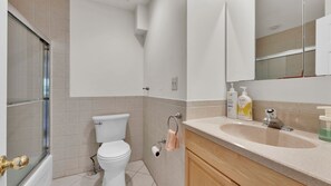 Un baño con inodoro, lavamanos, espejo y ducha.
