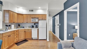 A modern kitchen with wooden cabinets, a microwave, a refrigerator, and a dishwasher. - Apartmint at 242 S 17th St Philadelphia (Philadelphia)