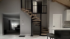 A modern kitchen with a wooden staircase leading to a lofted area. - Finger Lakes, Wine Country, Modern Escape (Montour Falls)