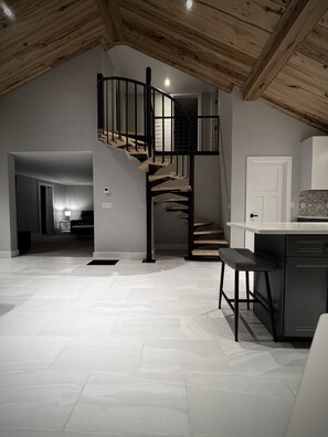 Eine moderne Küche mit einer Holztreppe, die zu einem erhöhten Bereich führt.