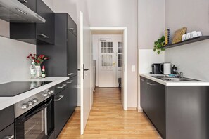 A modern kitchen with black cabinets, a white countertop, and a wooden floor. - SOLARIS - Vacation rental, sleeps 2, Old Town, kitchen, parking, Elbe River, S-Bahn, Wi-Fi (Meißen)