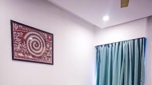 A neatly made bed with a red and white bedspread, a wooden headboard, and a wall-mounted artwork. - Hotel Paradise  (Rajgurunagar)