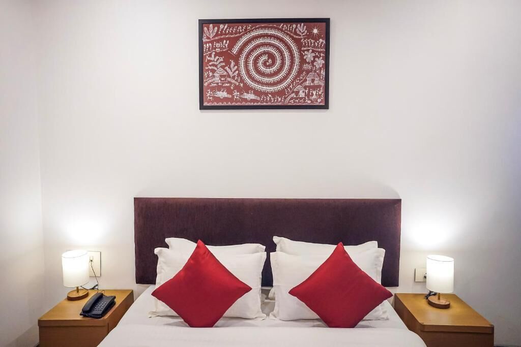 A hotel room with a bed, two nightstands, a wall-mounted artwork, and a headboard.