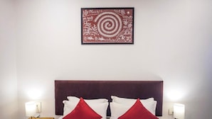 A hotel room with a bed, two nightstands, a wall-mounted artwork, and a headboard. - Hotel Paradise  (Rajgurunagar)