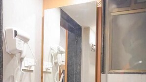 A bathroom with a white sink, a mirror, and two hair dryers mounted on the wall. - Hotel Paradise  (Rajgurunagar)