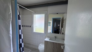 Ett badrum med duschdraperi, toalett, handfat och spegel.