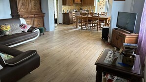 Una sala de estar con sofá, televisión y comedor con muebles de madera.