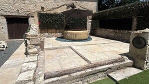 Un edificio de piedra con un patio empedrado, un jacuzzi y un pequeño jardín.