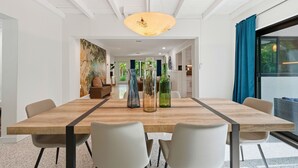 Un comedor moderno con una mesa de madera, sillas blancas y botellas de vidrio decorativas.