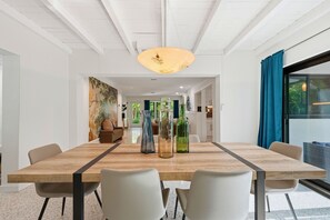 Un espace repas moderne avec une table en bois, des chaises blanches et des bouteilles en verre décoratives.