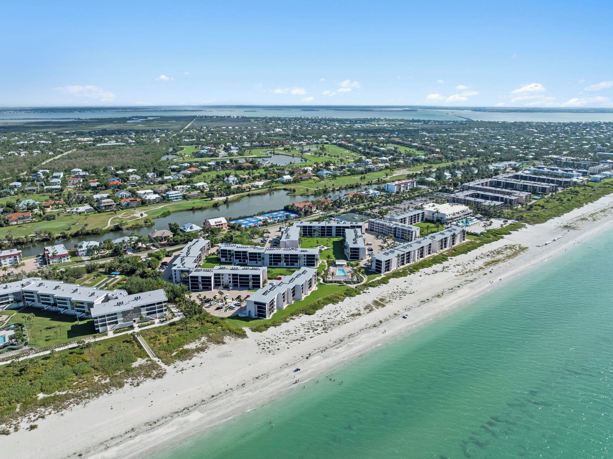 A coastal hotel with multiple buildings, a beach, and a marina.